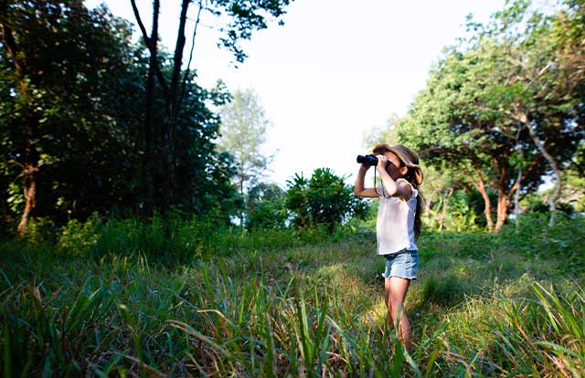 Girl looking through binoculars in a field