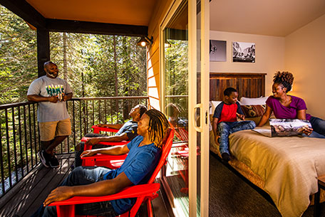 Family relaxing on the porch and bedroom of their Explorer Cabin at Tenaya Lodge at Yosemite